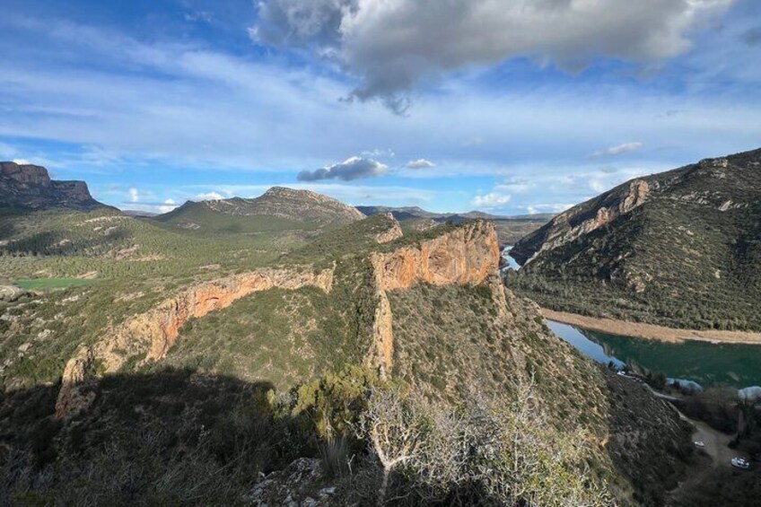 A rugged canyon landscape with a river, steep cliffs, and sparse vegetation. 4