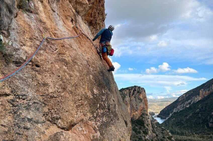 A person rock climbing on a steep cliff with a rope. 3