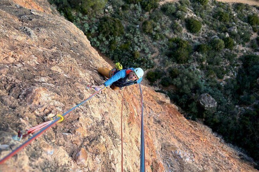 A person rappelling down a rocky cliff with safety ropes. 3