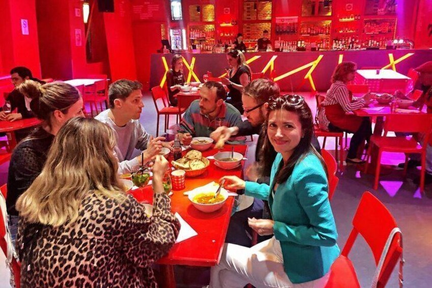 Un grupo de personas cenando en un restaurante con decoración roja y un bar al fondo. 4