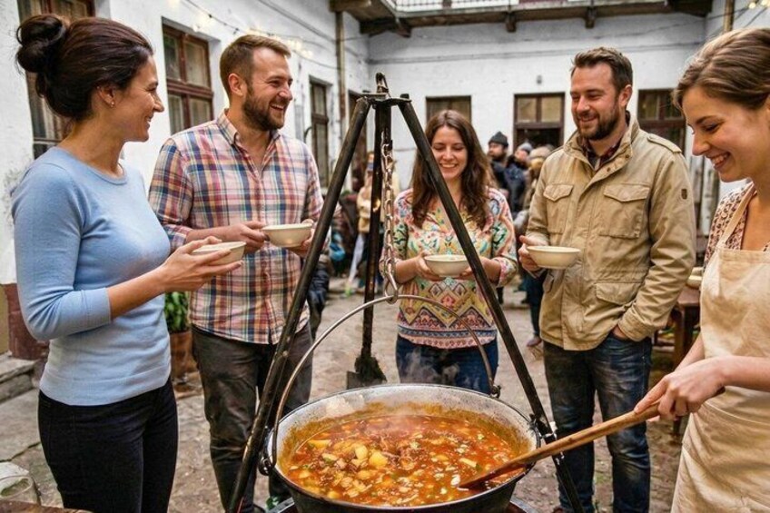 Un grupo de personas alrededor de una olla grande sobre un trípode, probablemente cocinando al aire libre. 1