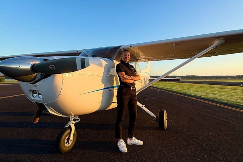 Ett litet flygplan står på en landningsbana och en person står bredvid det. 5