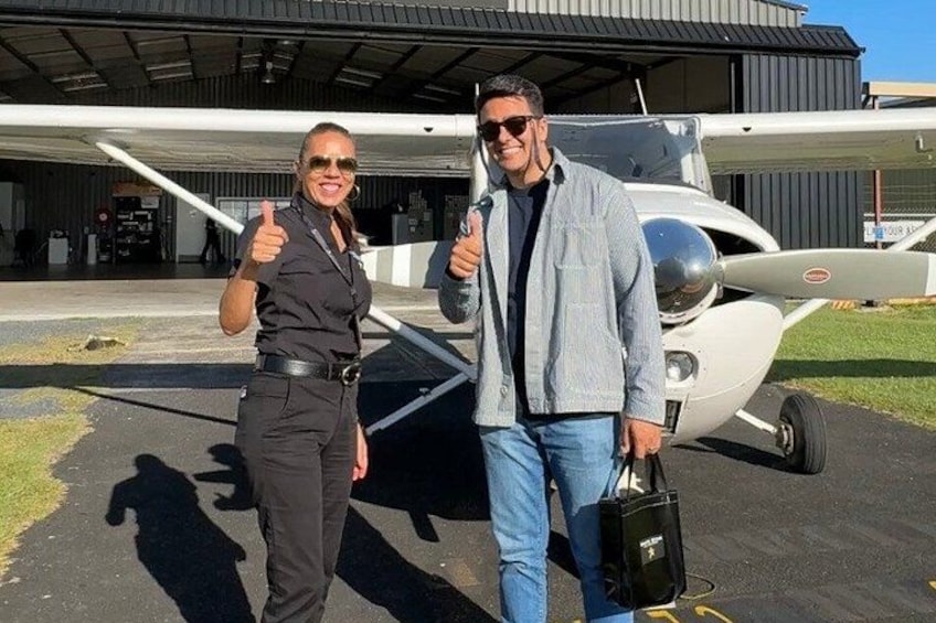Två personer står framför ett flygplan, med en hangar i bakgrunden. 3