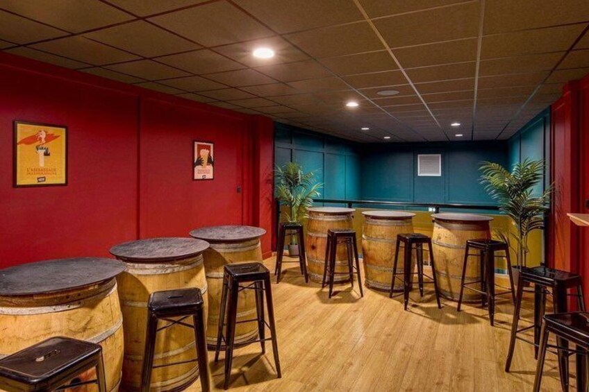 A bar area with wooden barrels, stools, and red walls. 3