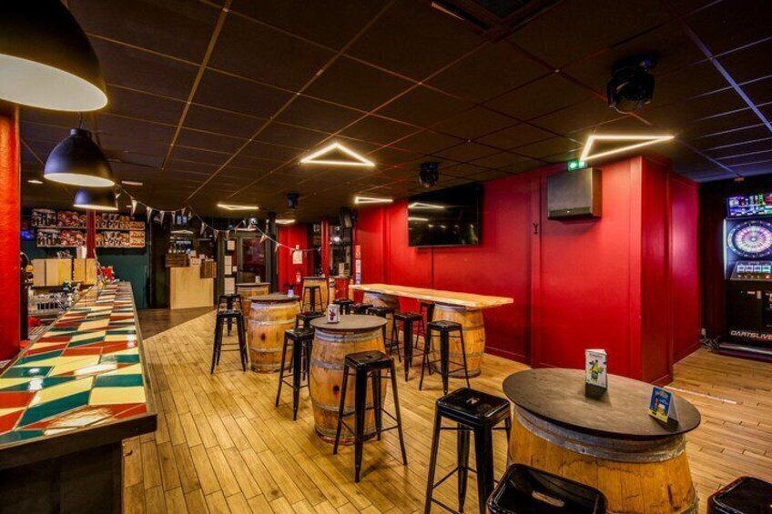 A bar with wooden floors, stools, and a dartboard. 4