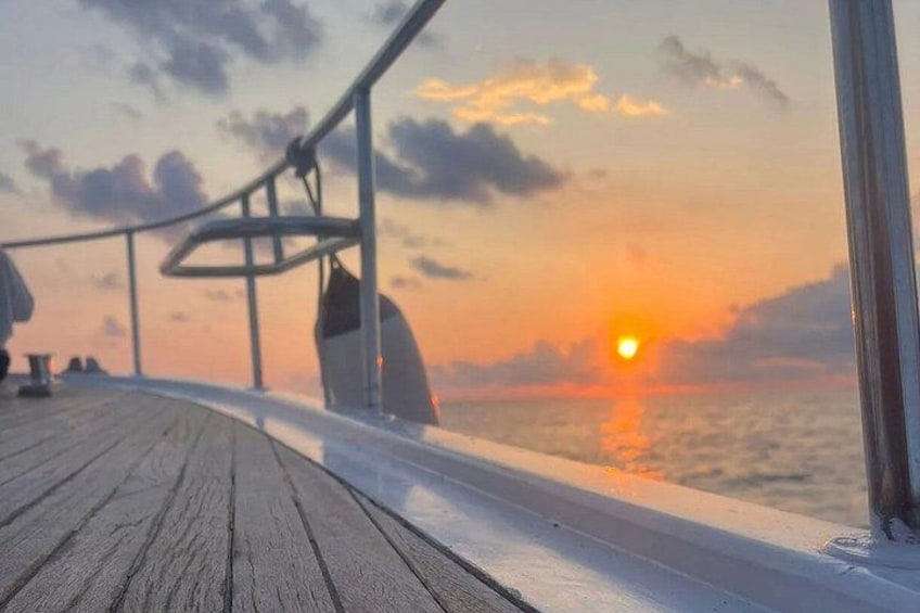 Un pontile in legno con ringhiera, un tramonto sull'oceano e cielo sereno. 4
