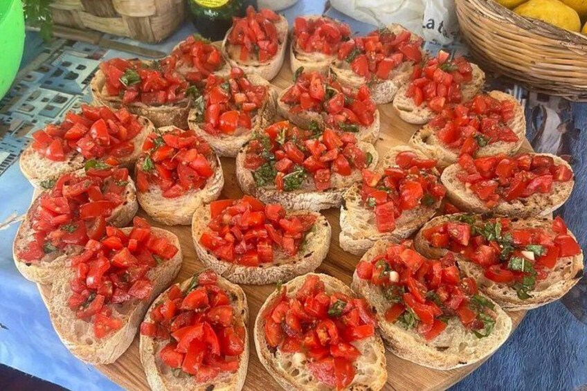 A wooden board with several pieces of bread topped with diced tomatoes and herbs. 2