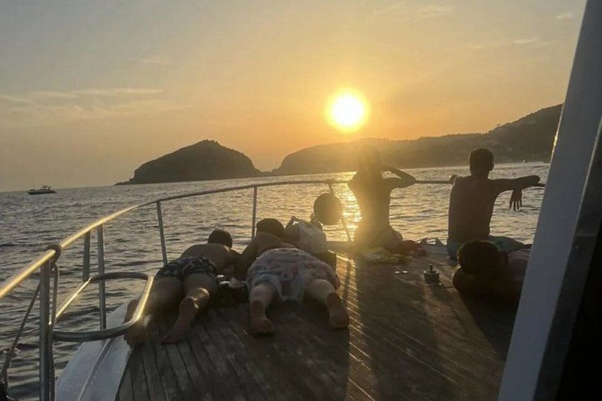 Tramonto sull'acqua con persone che si rilassano sul ponte di una barca. 2