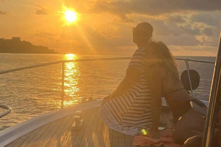 Una persona seduta sul ponte di una barca al tramonto. 1