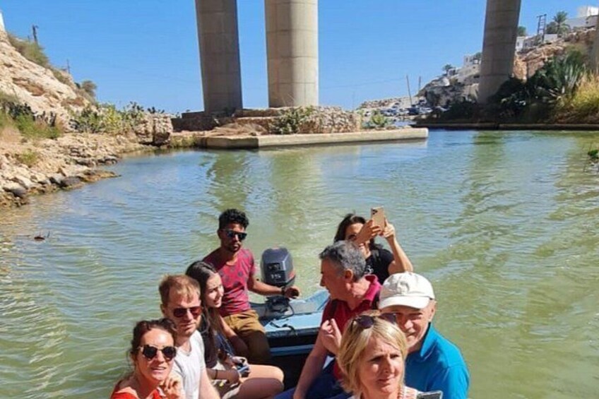Un grupo de personas en un bote cerca de un puente con pilares grandes. 1