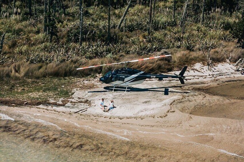 Un helicóptero en una playa arenosa con gente sentada cerca. 3