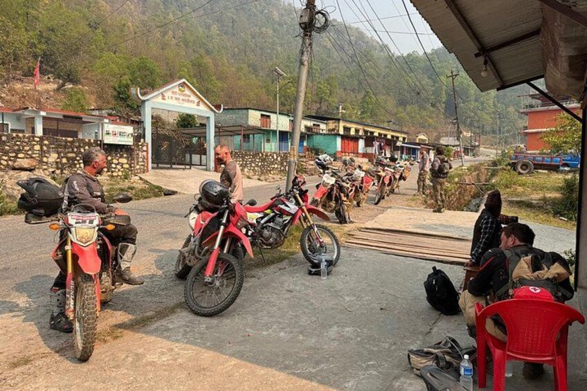 A group of motorcycles parked in a rural setting with a building in the background. 5