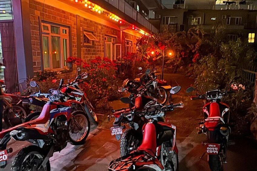 Motorcycles parked in front of a building with a brick facade and red flowers. 2