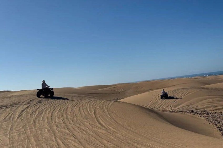 Zwei Personen fahren mit Quads durch eine Wüstenlandschaft mit Sanddünen. 2