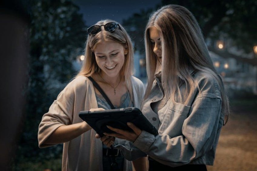 Two people standing outdoors, one holding a tablet. 4