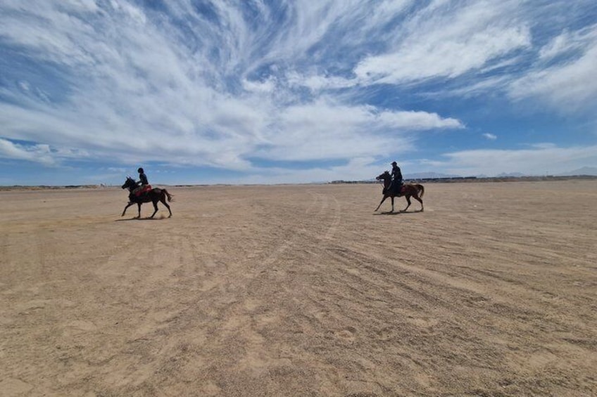 Deux cavaliers à cheval évoluent dans un vaste paysage ouvert, sous un ciel dégagé. 4