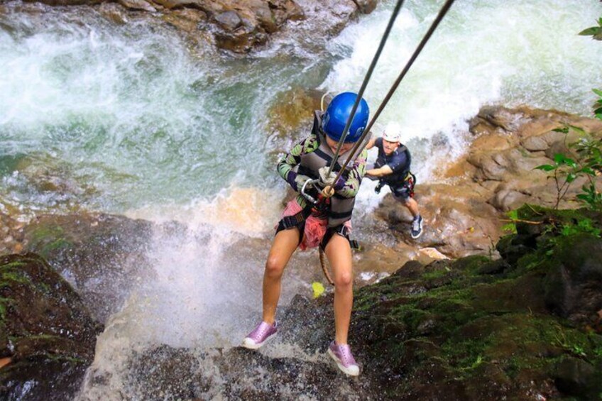 Una persona descendiendo en rappel por una cascada rocosa. 3