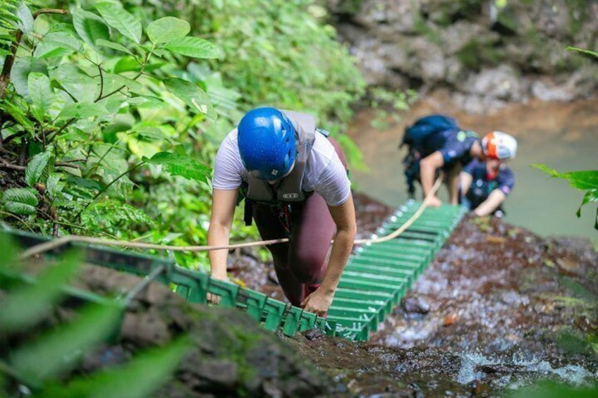Dos personas cruzando un puente verde sobre un arroyo en un área boscosa. 5