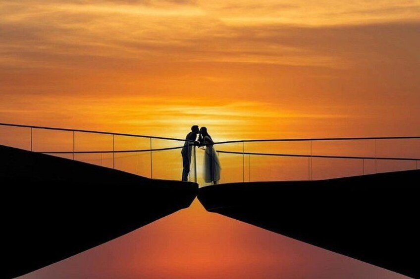 A sunset with silhouettes of two people on a bridge. 3