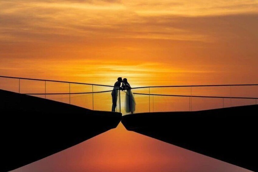 A sunset with two silhouetted figures on a bridge. 3