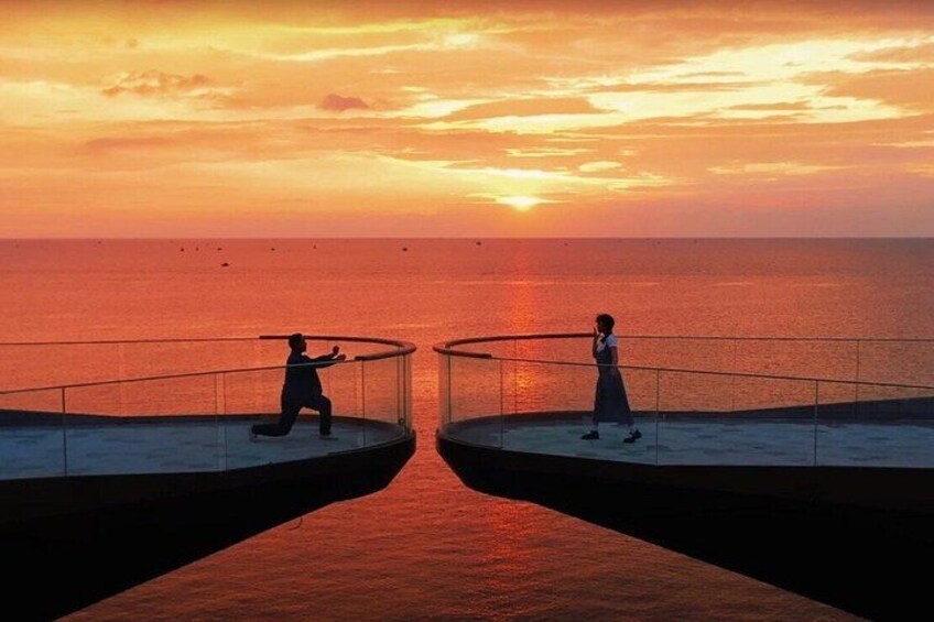 Two people on a balcony overlooking the sea at sunset. 5