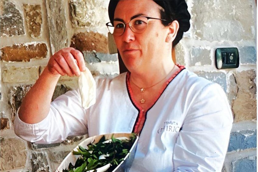 Une personne tenant un bol de légumes verts, vêtue d’une chemise blanche à col rouge, se tient devant un mur de briques. 1
