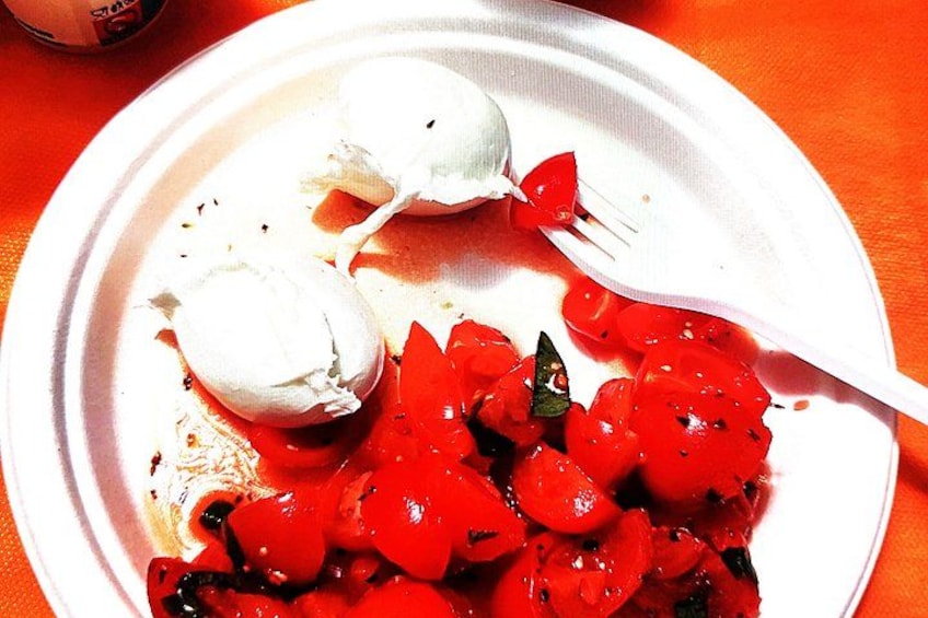 Une assiette en carton blanche, accompagnée d’une fourchette, contient une salade de tomates et deux portions d’une préparation blanche, qui pourrait être de la crème glacée ou du yaourt glacé. 2