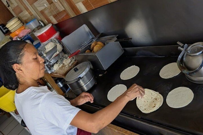 Iemand bereidt tortilla's op een groot, vlak kookoppervlak. 1