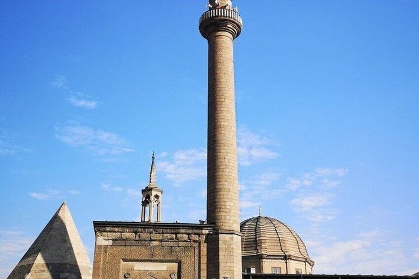 A tall minaret, a pyramid, and a dome under a clear sky. 3