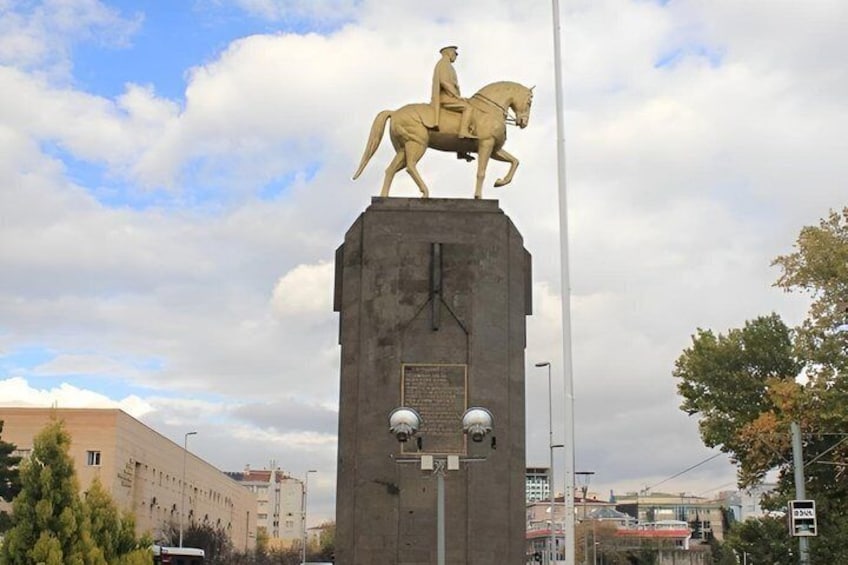 A statue of a figure on horseback atop a monument with a plaque and two spherical objects below. 5