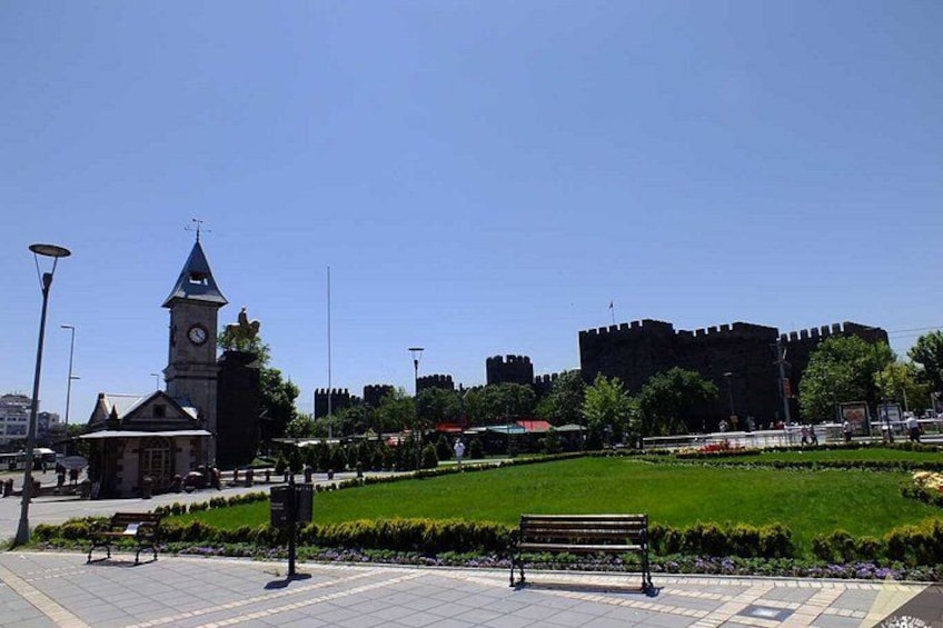 Ein Park mit einem Uhrturm, einer Burg und einer Bank. 4