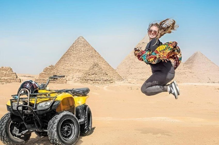 En person som hoppar framför pyramiderna, med en fyrhjuling i bakgrunden. 3