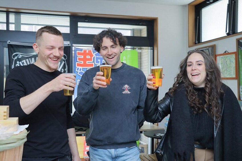 Tre personer holder glas, et skilt med kinesiske tegn, og et vindue. 2