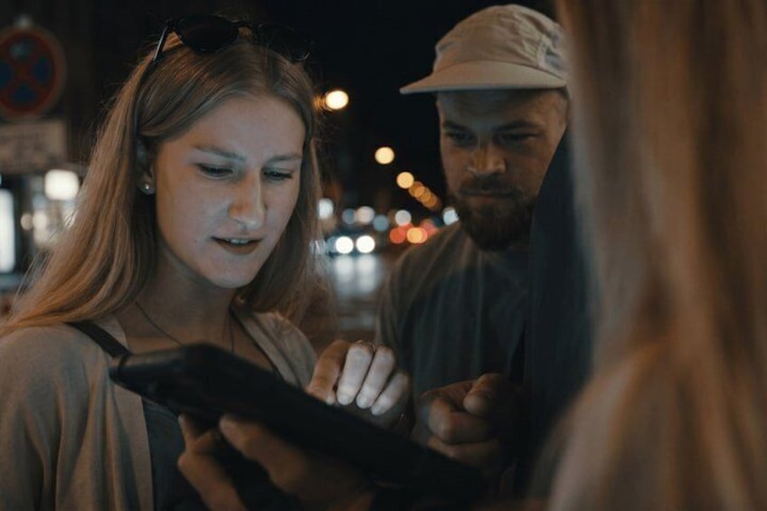 Two people standing on a street at night, one holding a smartphone. 2