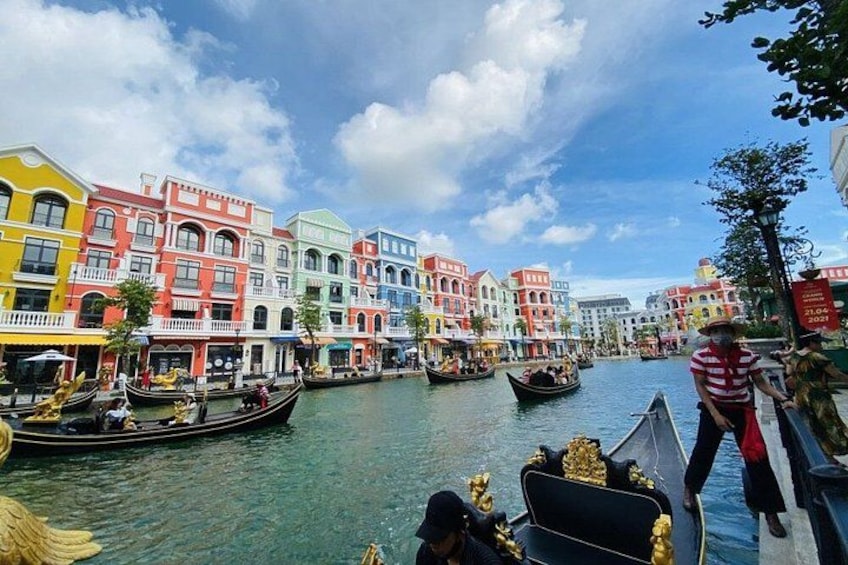 A canal with colorful buildings on one side and gondolas on the water. 1