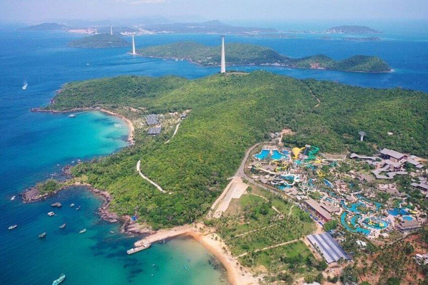 An aerial view of a coastal resort with a lighthouse, turquoise waters, and lush greenery. 3
