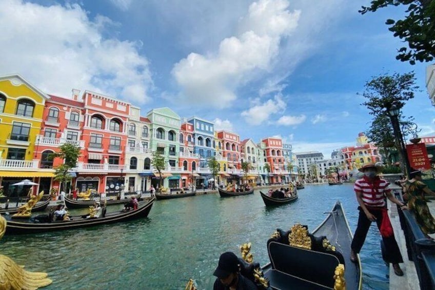 A canal with colorful buildings, gondolas, and a person in a striped shirt. 1