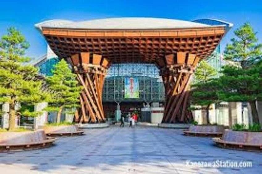 A modern architectural structure with a unique roof design, surrounded by trees and a clear sky. 2