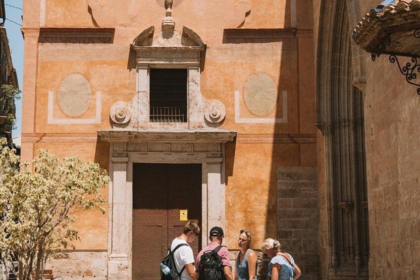 Un grupo de personas de pie frente a un edificio con una puerta grande y una ventana pequeña arriba. 4