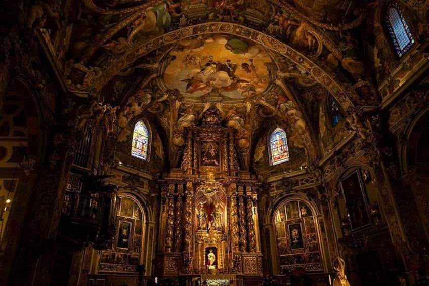 Interior de iglesia ornamentado con frescos detallados, vidrieras y un altar central. 5