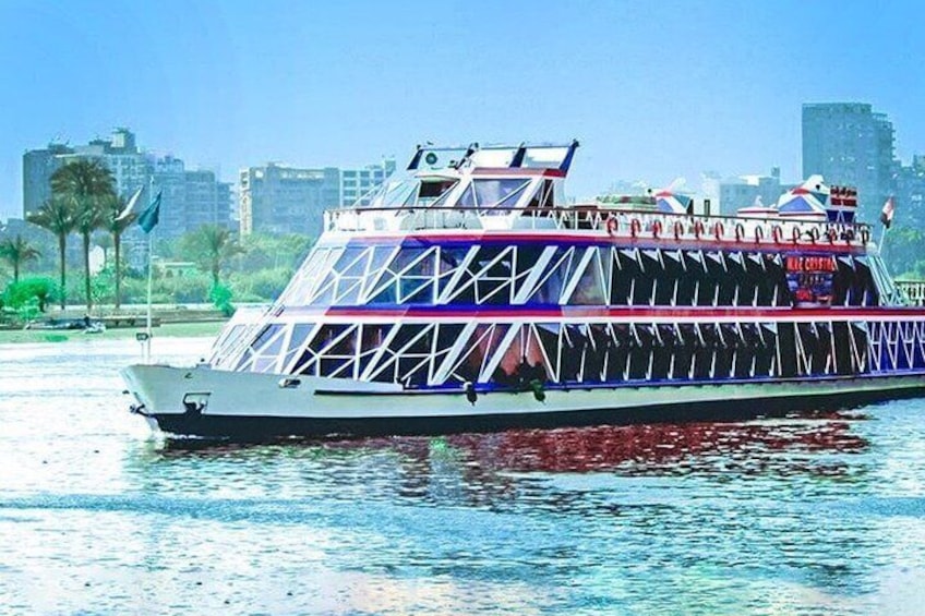 A large, colorful boat with a unique geometric design, floating on water with a city skyline in the background. 1