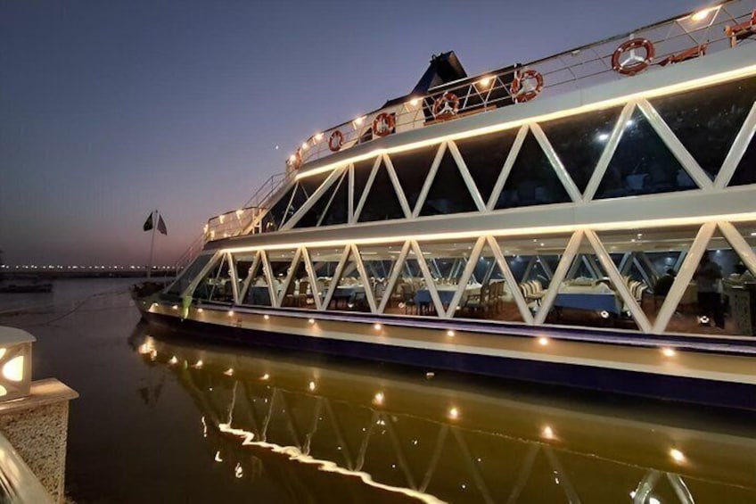 A large illuminated boat with a truss structure, docked at a pier. 3