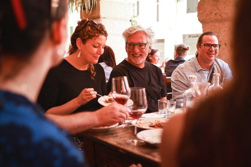 Gæster spiser på en udendørs restaurant med borde, vinglas og tallerkener. 5