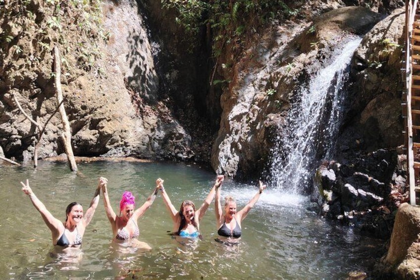 A group of people in a natural setting with a waterfall and rocky terrain. 4