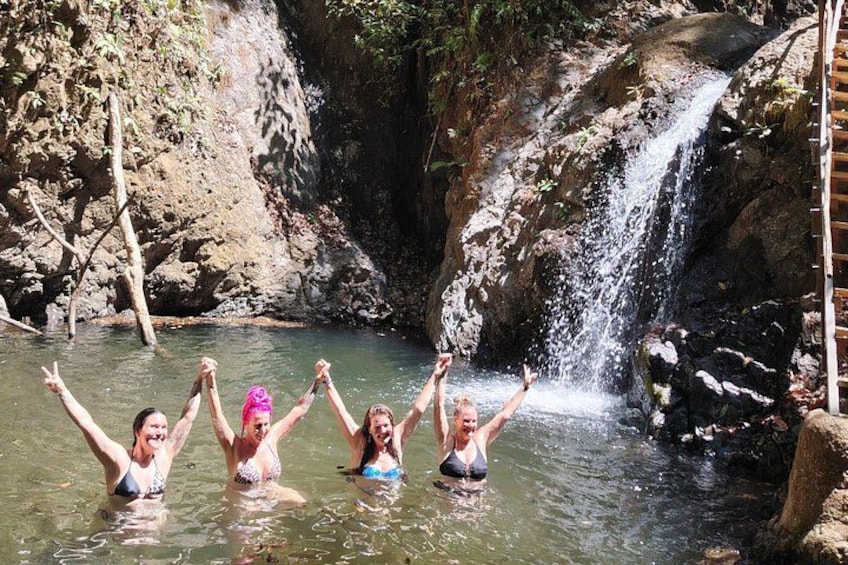 A group of people in a natural setting with a waterfall and rocky terrain. 4