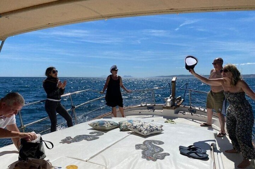 A group of people on a boat with a clear view of the sea and distant land. 2