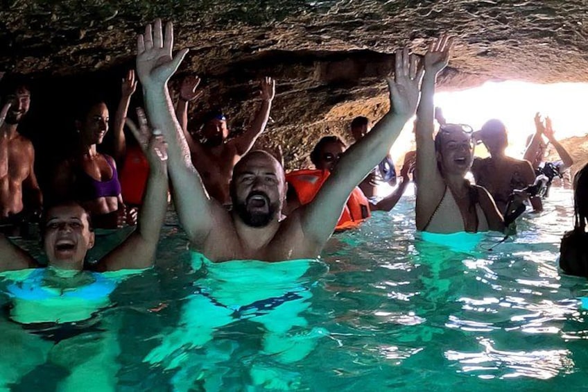 People swimming in a pool with a cave-like structure in the background. 2