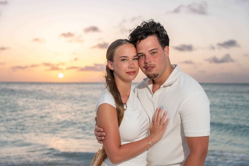 A couple embracing on a beach with the ocean and a sunset in the background. 2