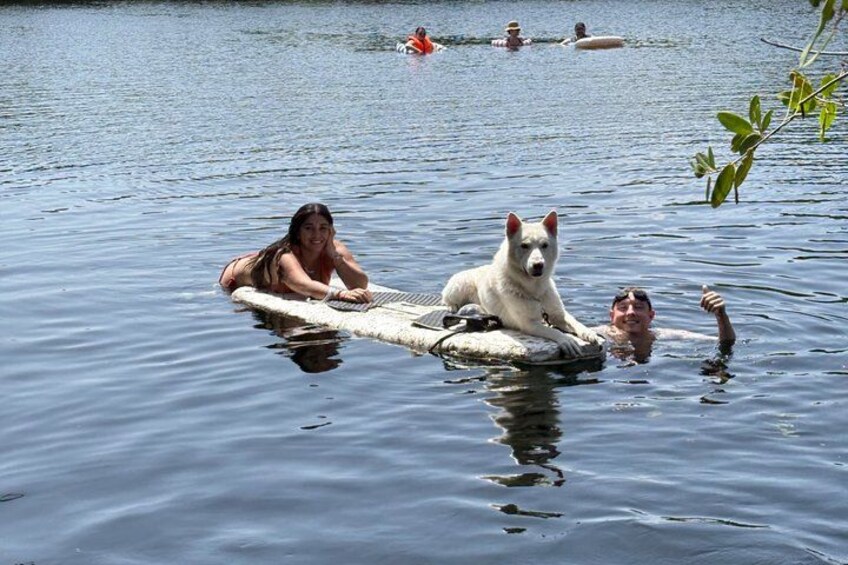 A person lying on a raft in a body of water with a dog. 4