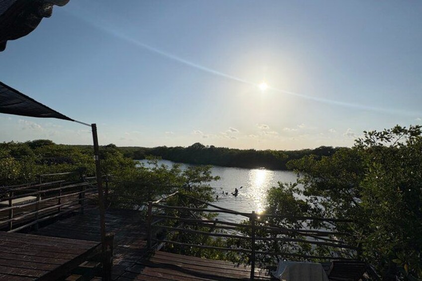 A wooden deck overlooking a calm lake with a clear sky and distant hills. 5